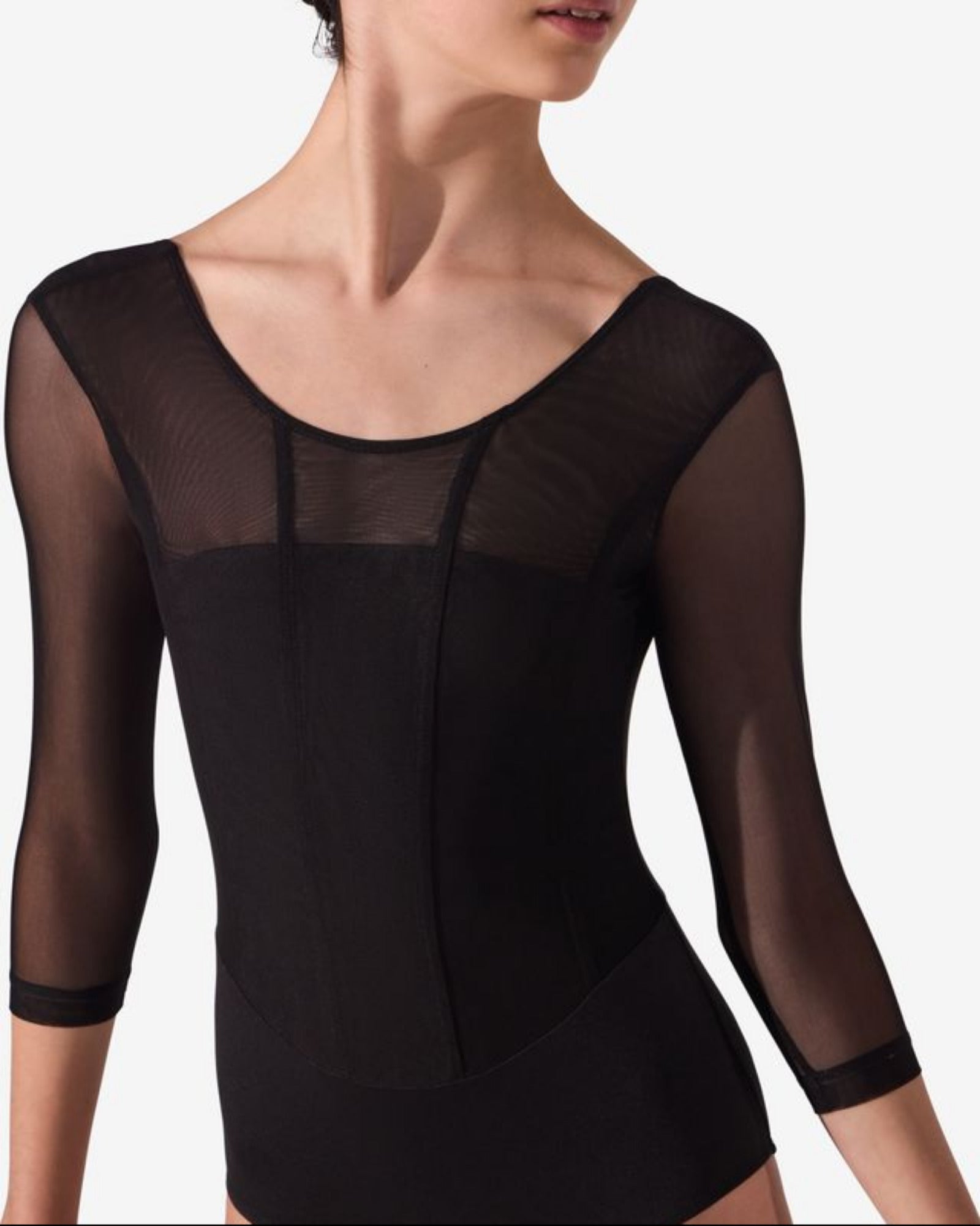 A female dancer wearing a black leotard with sheer three-quarter sleeves and a scoop neckline, shown against a plain light gray studio background.