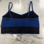 A blue and black dance bra laid flat on a white marble surface.