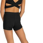 A young girl shown from the back wearing a black dance two-piece set consisting of a strappy sports bra and matching high-waisted shorts, set against a plain white background.