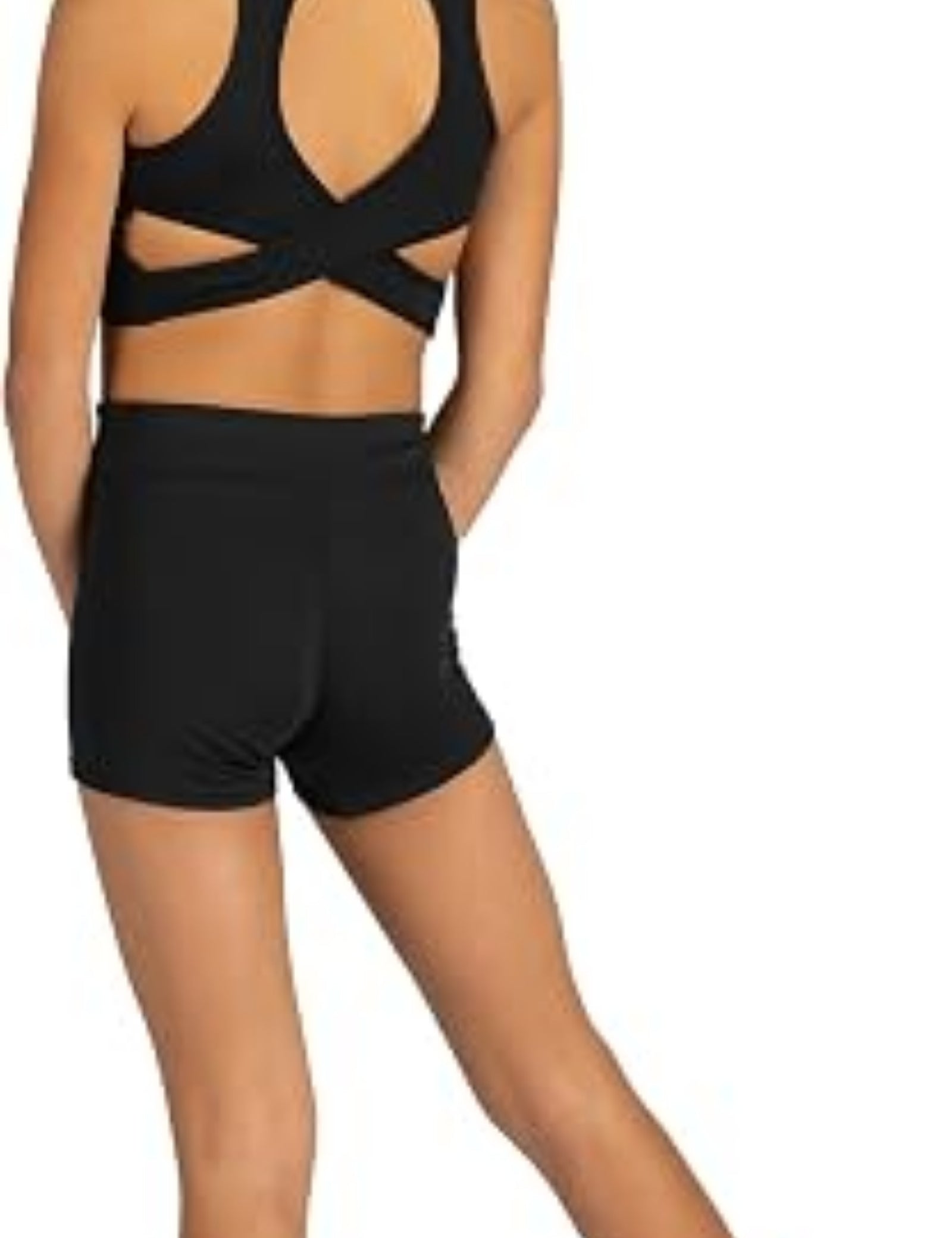 A young girl shown from the back wearing a black dance two-piece set consisting of a strappy sports bra and matching high-waisted shorts, set against a plain white background.
