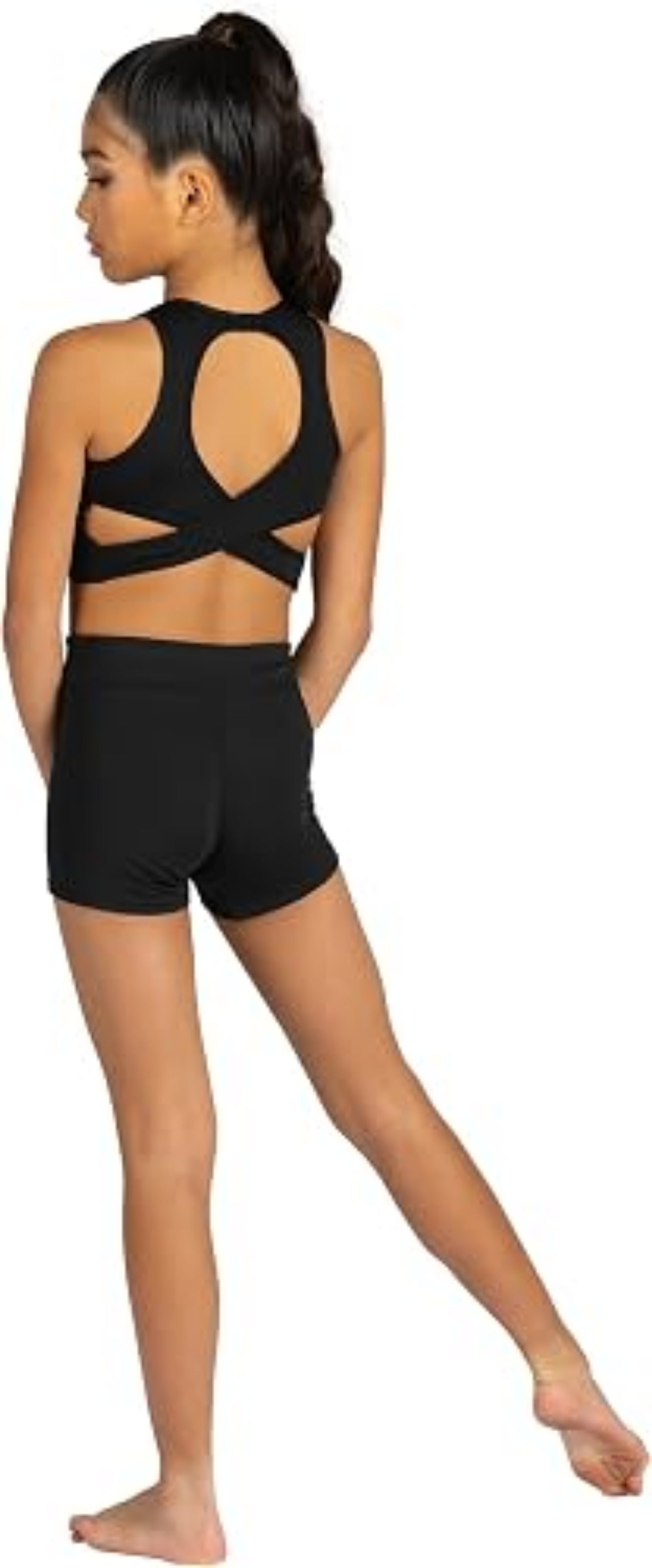 A young girl shown from the back wearing a black dance two-piece set consisting of a strappy sports bra and matching high-waisted shorts, set against a plain white background.