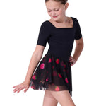 Young girl wearing a black dress with red strawberry patterns on the skirt on a white background