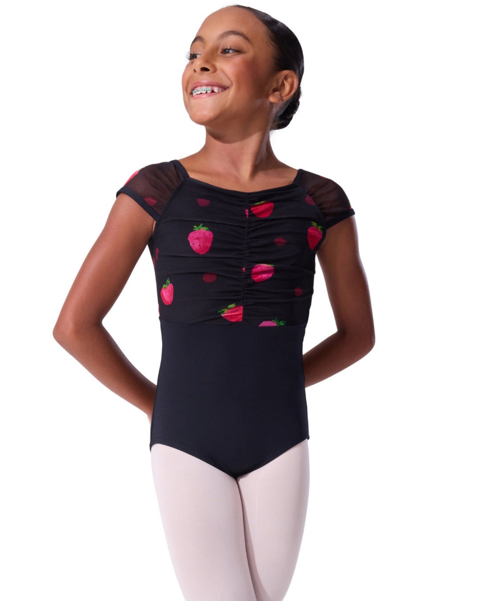 Young girl wearing a black leotard with strawberry patterns on a white background