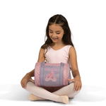 Young girl holding a pink and purple bag with ballet shoes design on a white background