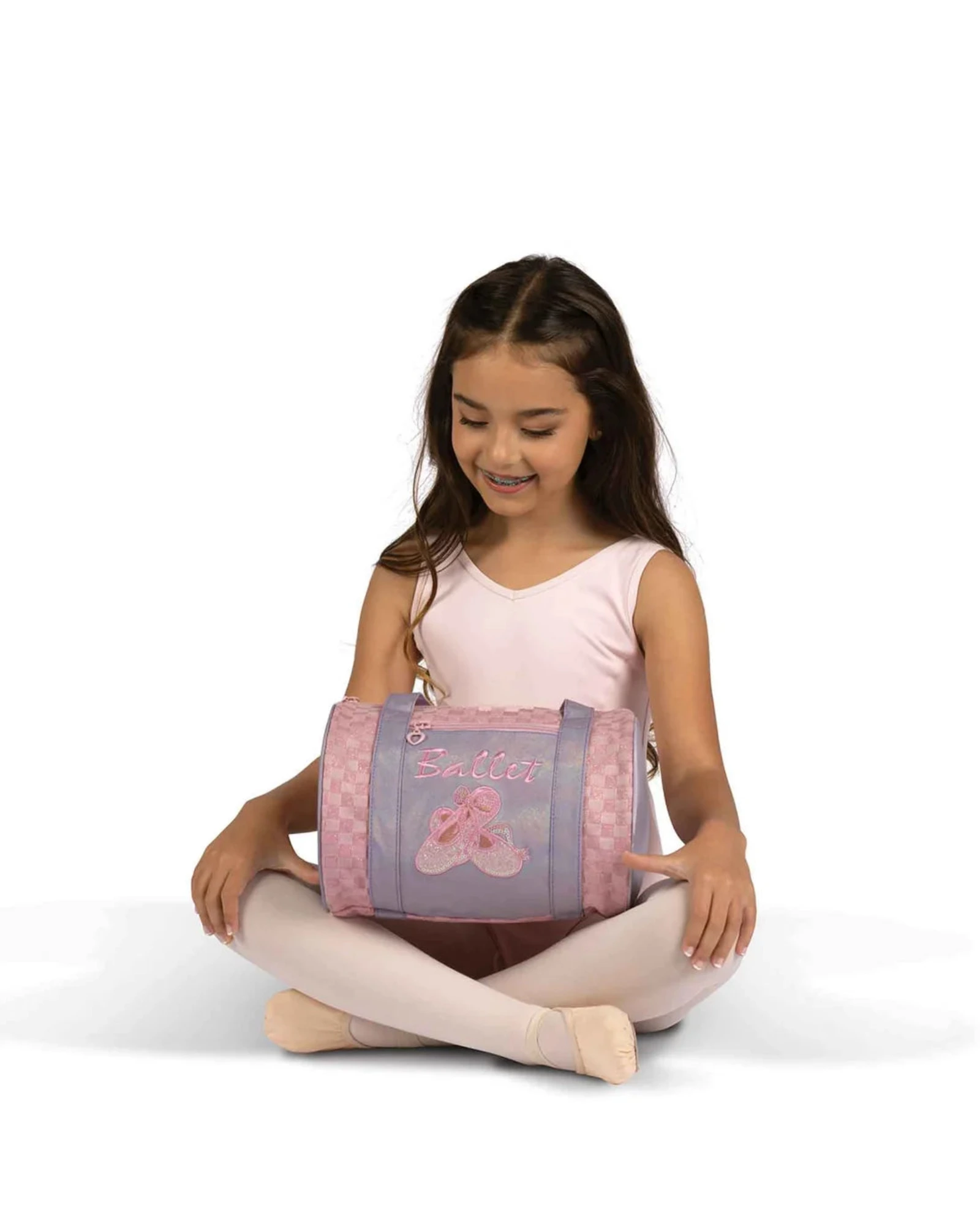 Young girl holding a pink and purple bag with ballet shoes design on a white background