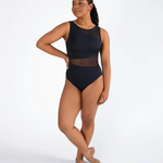 A woman modeling a sleeveless black dance leotard with sheer mesh panels, standing in ballet slippers against a plain white studio background.