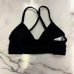 A navy dance bra with crossover straps, laid flat on a white marble surface.