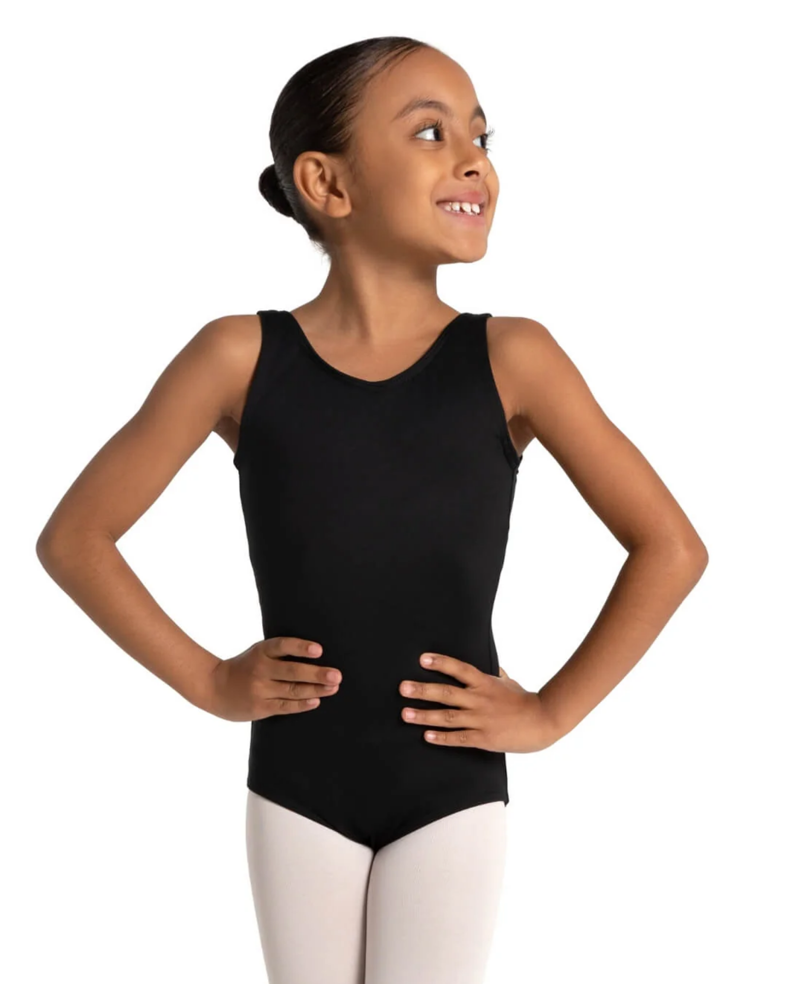 A young girl with her hair in a bun poses in a sleeveless black dance leotard and white tights against a solid white background.