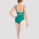 A female dancer shown from the back wearing a teal green leotard with a crossover back design, paired with light pink tights and pointe shoes, against a light gray studio background.