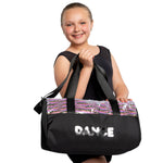 Young girl holding a black dance bag with 'DANCE' written on it against a white background