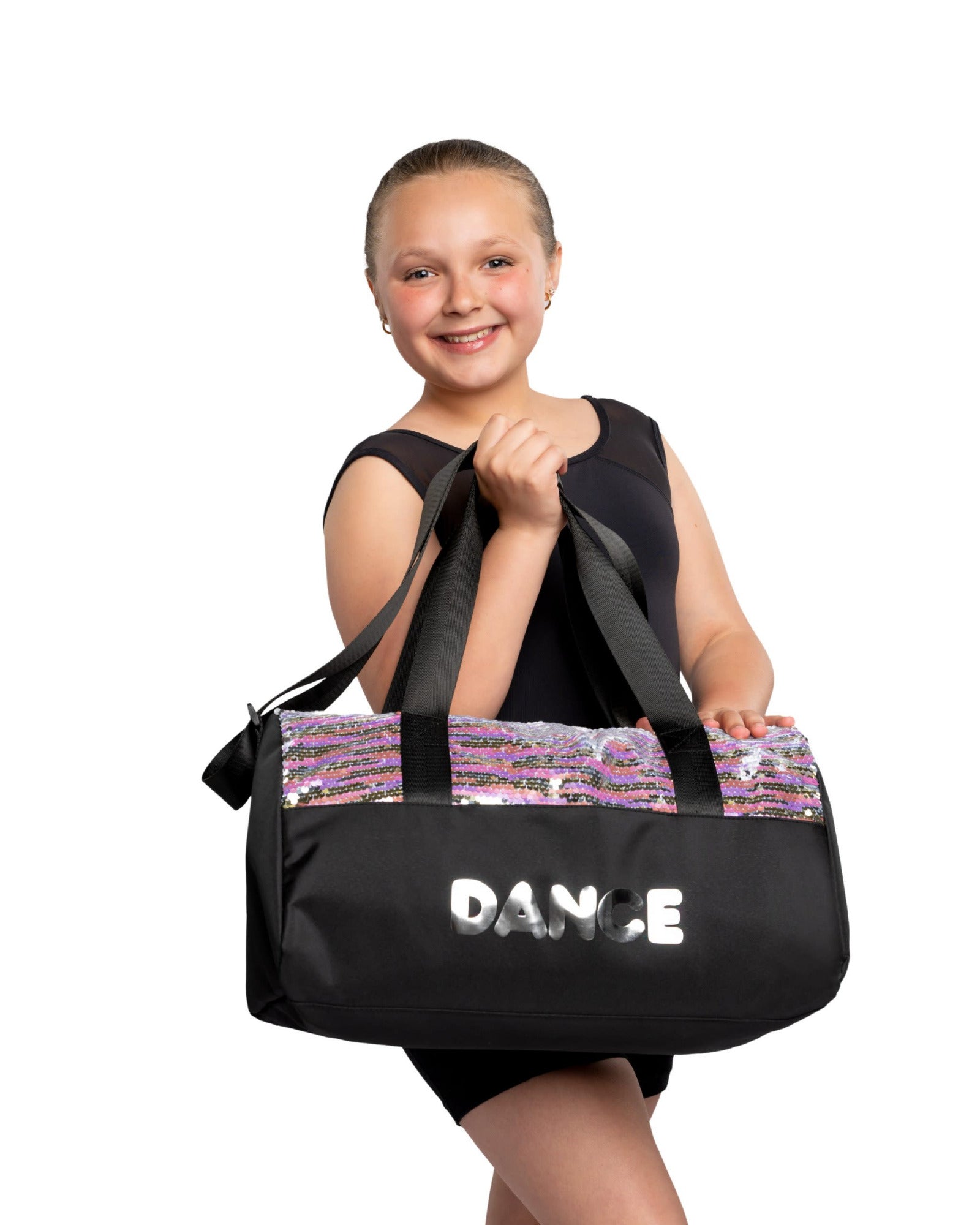 Young girl holding a black dance bag with 'DANCE' written on it against a white background