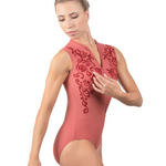 Woman wearing a rust colored leotard with intricate designs on a white background