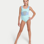A young girl modeling a light blue leotard with a light mint green and light blue geometric pattern on the chest, standing against a solid light gray background. 