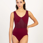 A woman modeling a sleeveless burgundy leotard with a V-neckline and sheer mesh paneling, set against a plain white studio background.