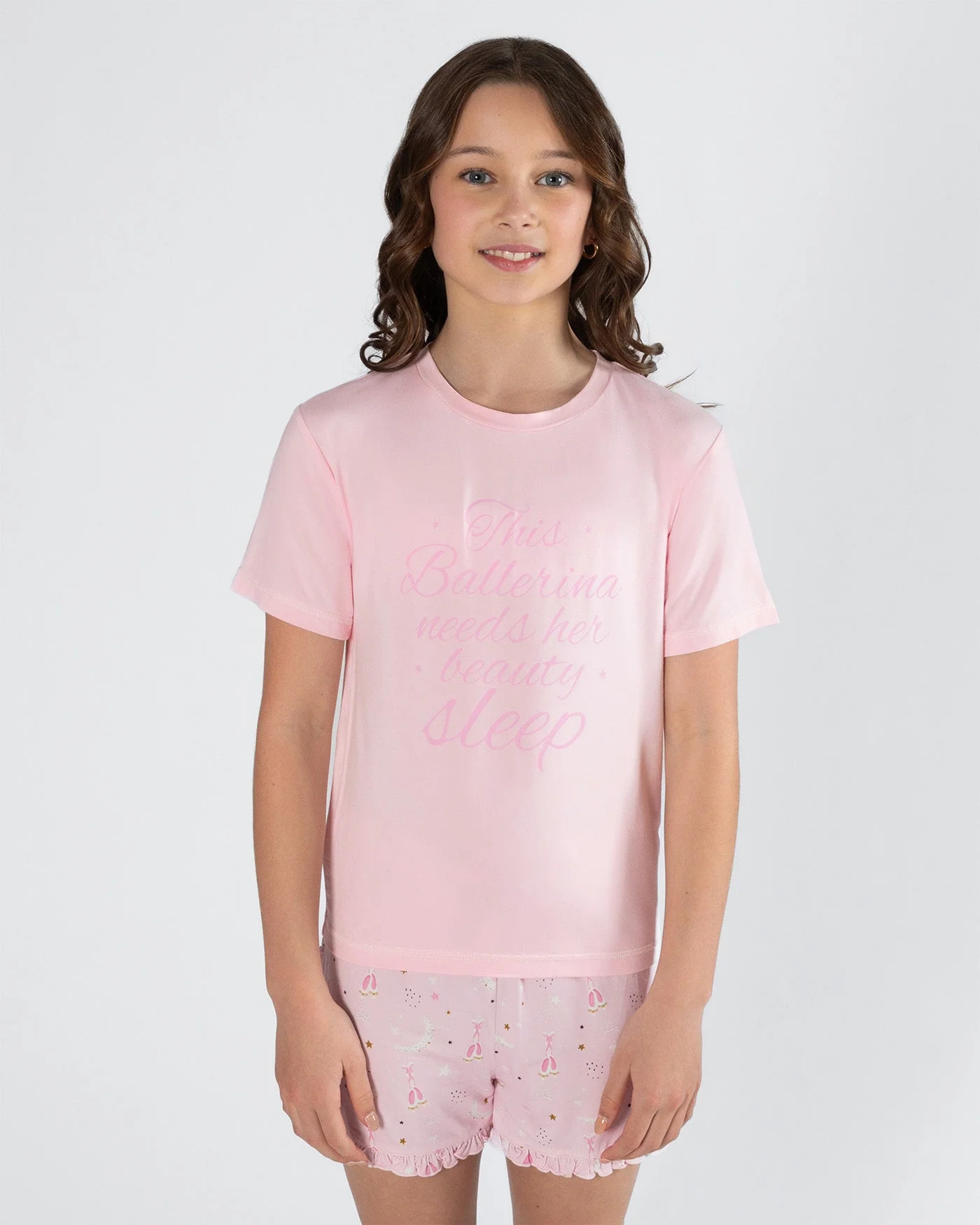 Young girl wearing a pink pajama set with a white background