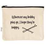 A canvas pouch in a natural beige color with a black zipper and printed black text that reads 'Wherever my bobby pins go, I hope they're happy.' accompanied by a simple illustration of crossed bobby pins.