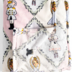 A folded plush blanket with a soft pink and white background, featuring a whimsical print of Sugar Plum Fairies, a mouse in a royal outfit, and delicate gray floral vine motifs.