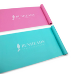 Two rolled-up exercise mats, one pink and one blue, with 'Bunheads' branding on a white background.