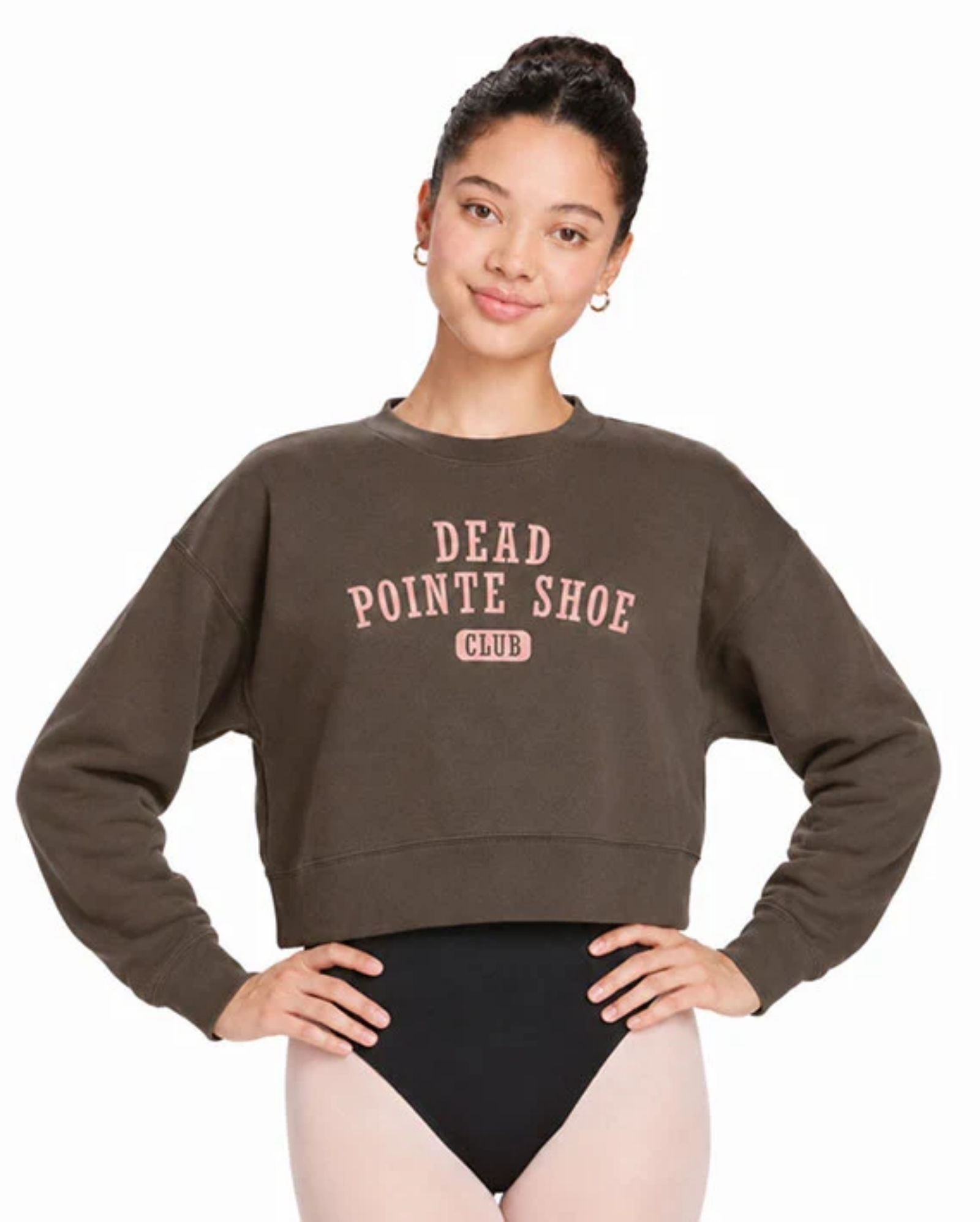 A woman modeling a dark brown cropped sweatshirt with 'DEAD POINTE SHOE CLUB' printed in pink on the front, paired with black and pink leggings, against a plain white background.