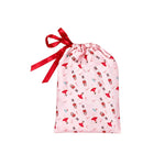 A light pink drawstring gift bag with a red ribbon bow, featuring a repeating pattern of red and black lipstick tubes and small red lipstick marks.