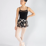 Dancer wearing a black leotard and floral skirt on a white background