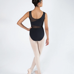 A female dancer shown from the back wearing a black sleeveless leotard with sheer mesh panels and light pink tights, standing in pointe shoes against a light gray studio background.