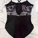 A leotard laid flat on a white marble surface. The bottom half is solid black, while the upper bust and underwire area feature a paisley pattern in black, dusty pink, and white.