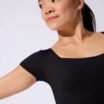 Woman wearing a black leotard against a plain background