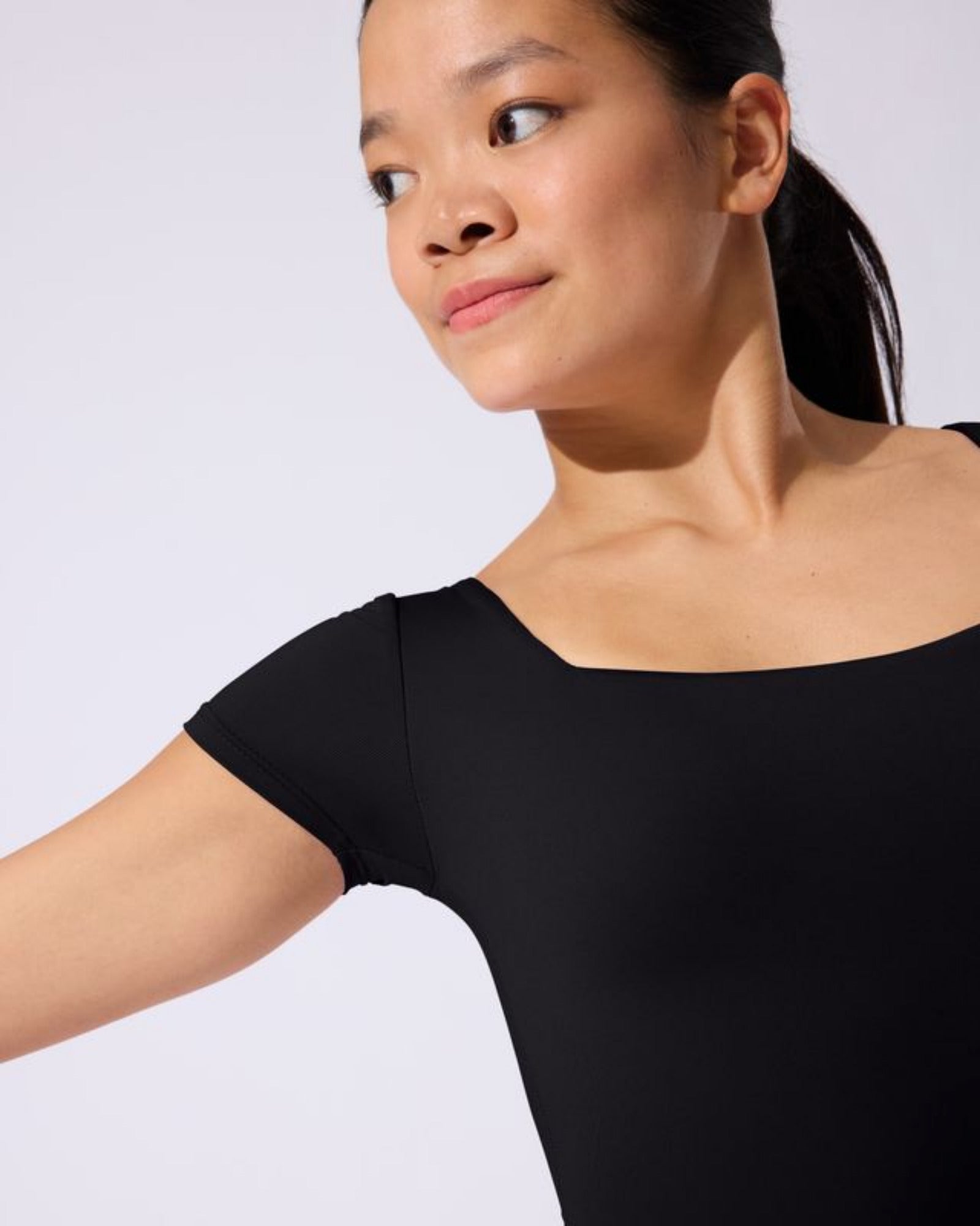 Woman wearing a black leotard against a plain background