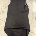 A dark black sleeveless leotard with a mock neck and front zipper, laid flat on a white marble surface.