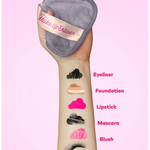 Makeup Eraser being used on a hand with makeup samples labeled on a pink background