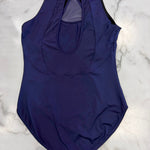 A sleeveless dark purple leotard with a keyhole back cutout, laid flat on a white and gray marble surface.