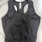 A dark heather gray racerback crop top laid flat on a white marble surface.