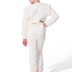 Person wearing a white outfit with ruffled sleeves on a white background