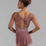 Woman wearing a mauve leotard with a skirt on a gray background