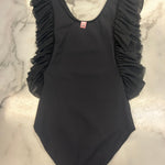 A black sleeveless leotard with dramatic ruffled shoulder details, laid flat on a white and gray marble surface.