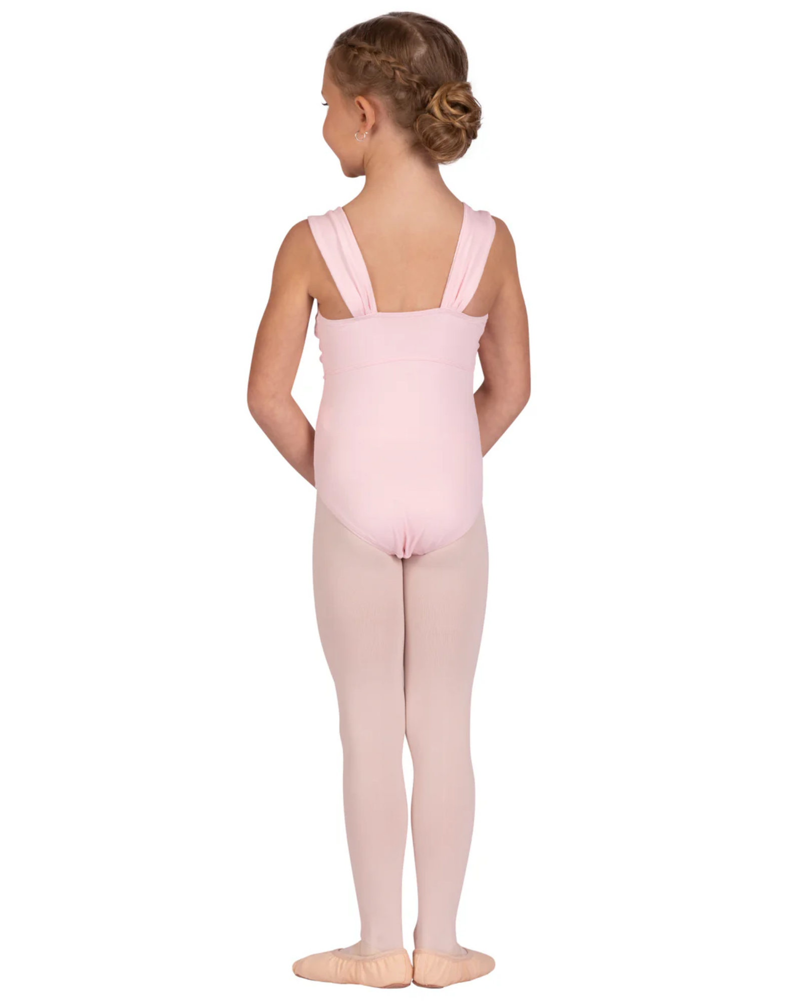 A young girl with her hair in a bun is shown from the back wearing a light pink tank dance leotard and matching pink tights against a solid white background.