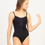 A woman modeling a black leotard with thin shoulder straps and a structured front, photographed against a plain light background.