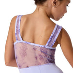 Woman wearing a sheer back leotard with floral pattern on a white background