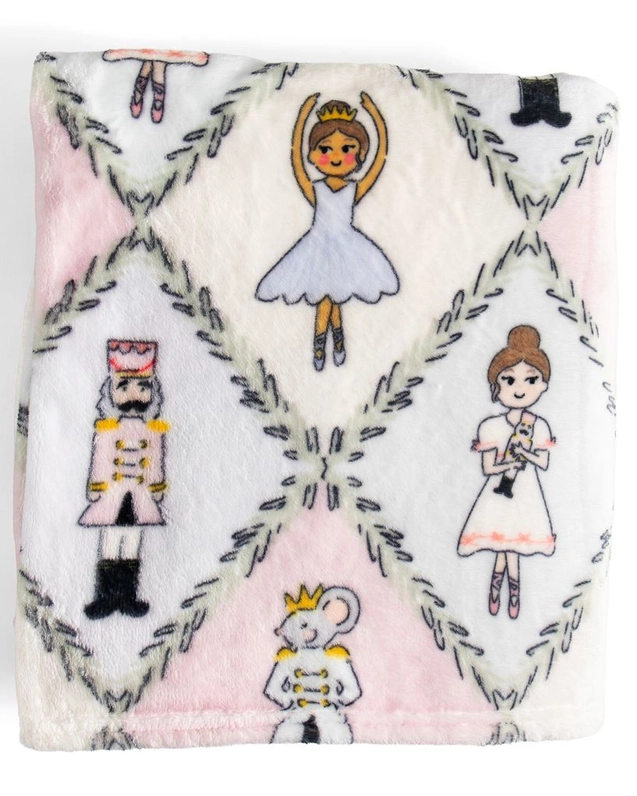 A square white plush blanket featuring a repeating pattern of ballet dancers, a nutcracker, a princess, a mouse prince, and gray geometric diamond borders.