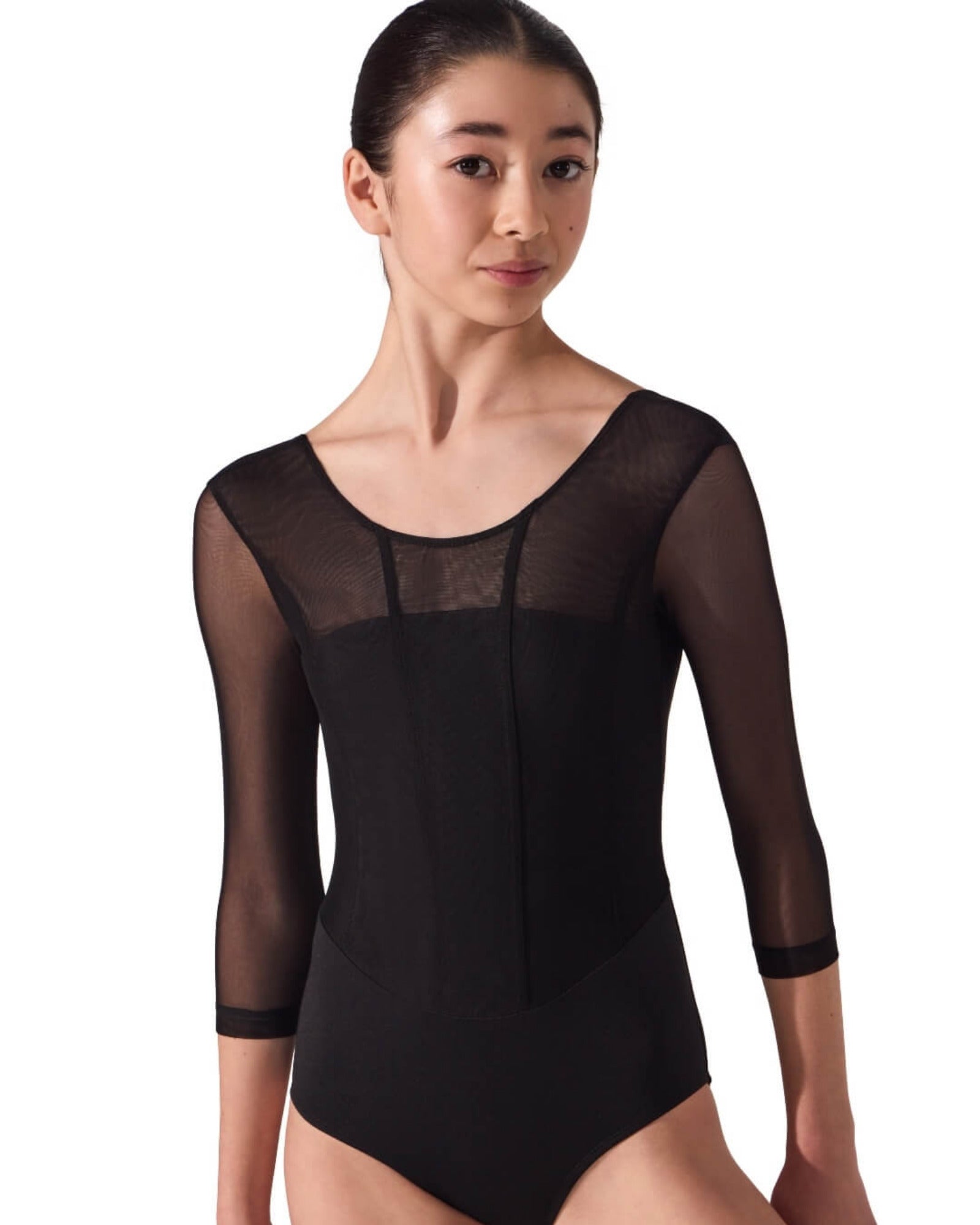 Woman wearing a black ballet leotard with sheer mesh panels on a white background