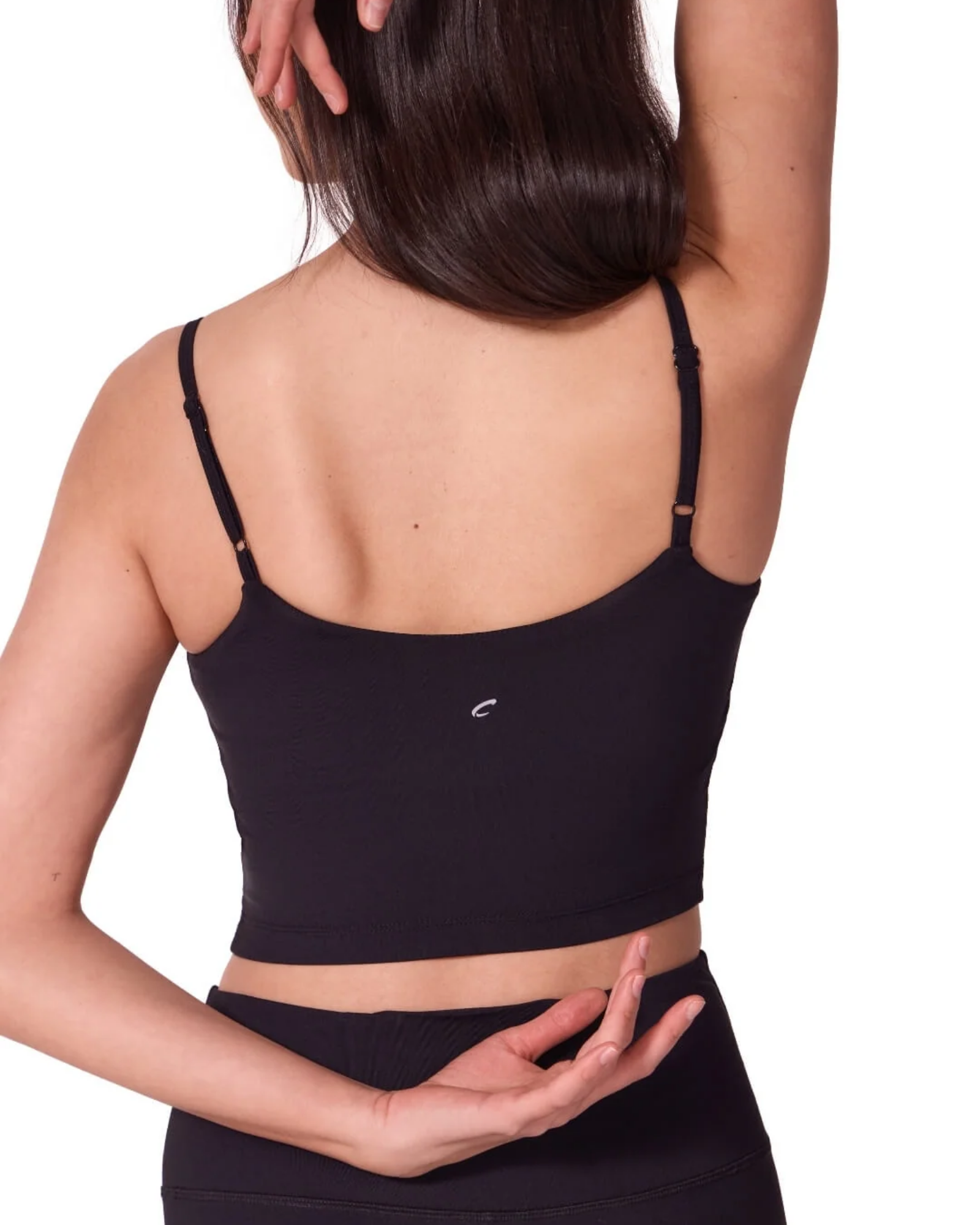 Person wearing a black dance bra and leggings on a white background