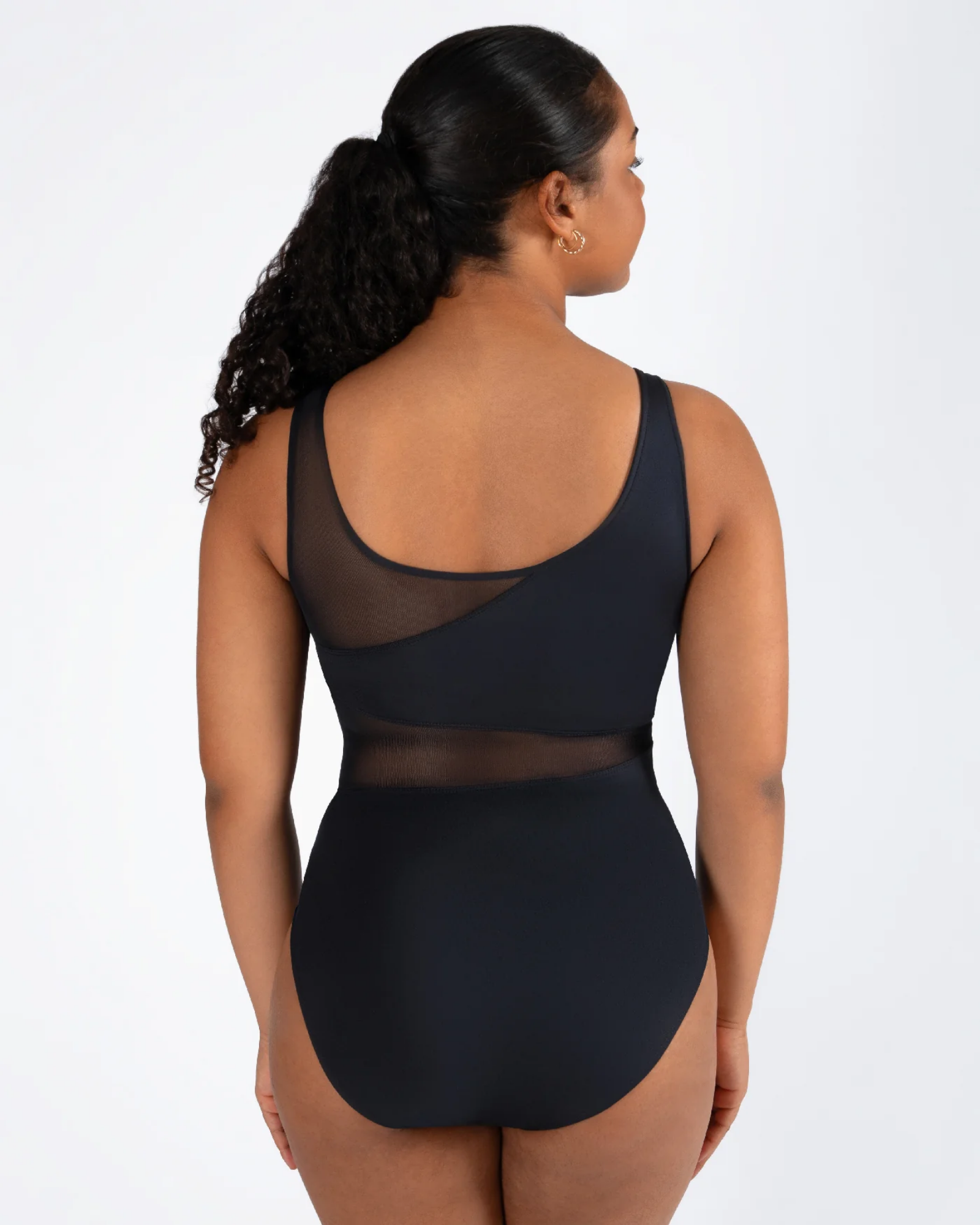 Woman wearing a black leotard with mesh panels on a white background