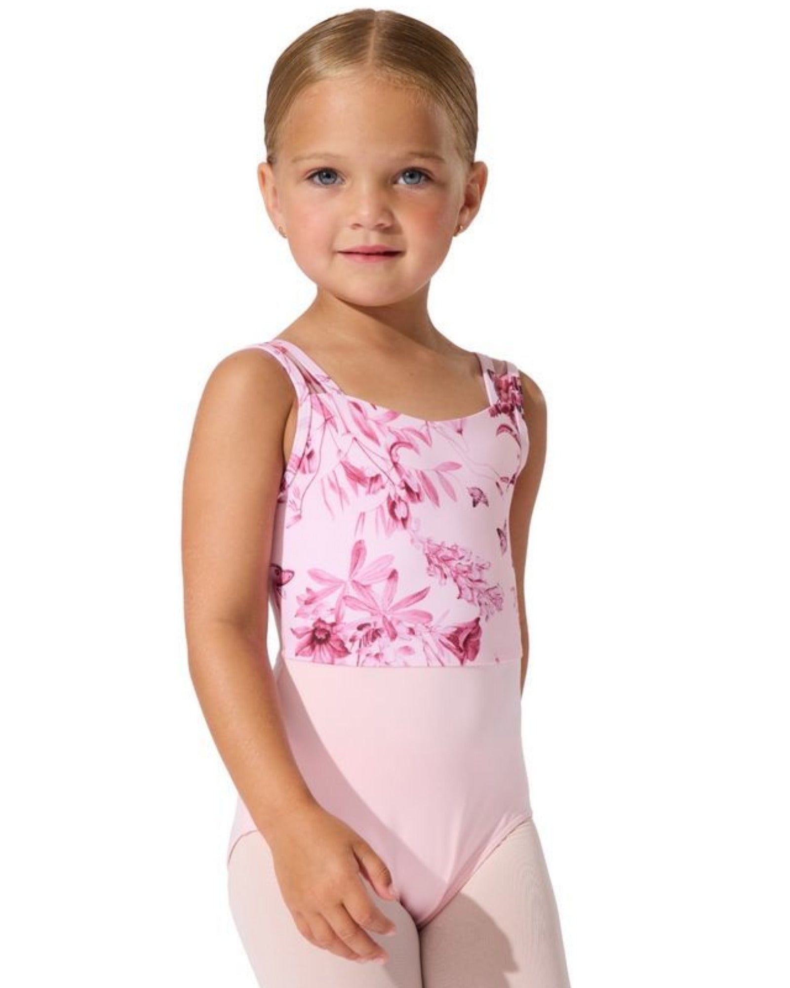 A young girl modeling a pink tank leotard with a darker pink floral pattern across the chest and shoulders, paired with light pink tights, against a plain white background.