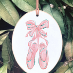 Decorative ornament with pink ballet shoes and bow on a leafy background
