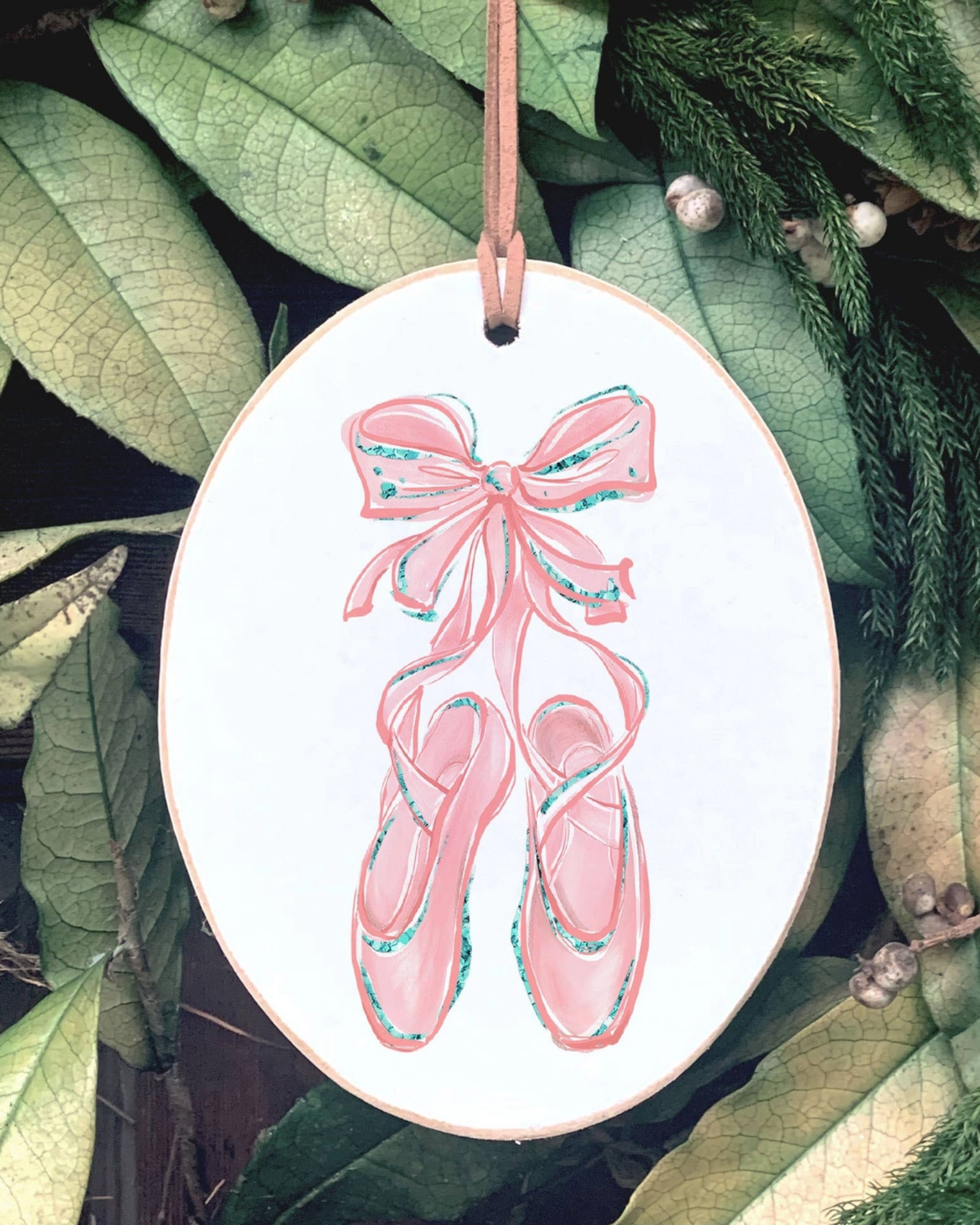 Decorative ornament with pink ballet shoes and bow on a leafy background