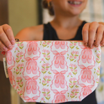 Person holding a pink pouch with ballet slipper design