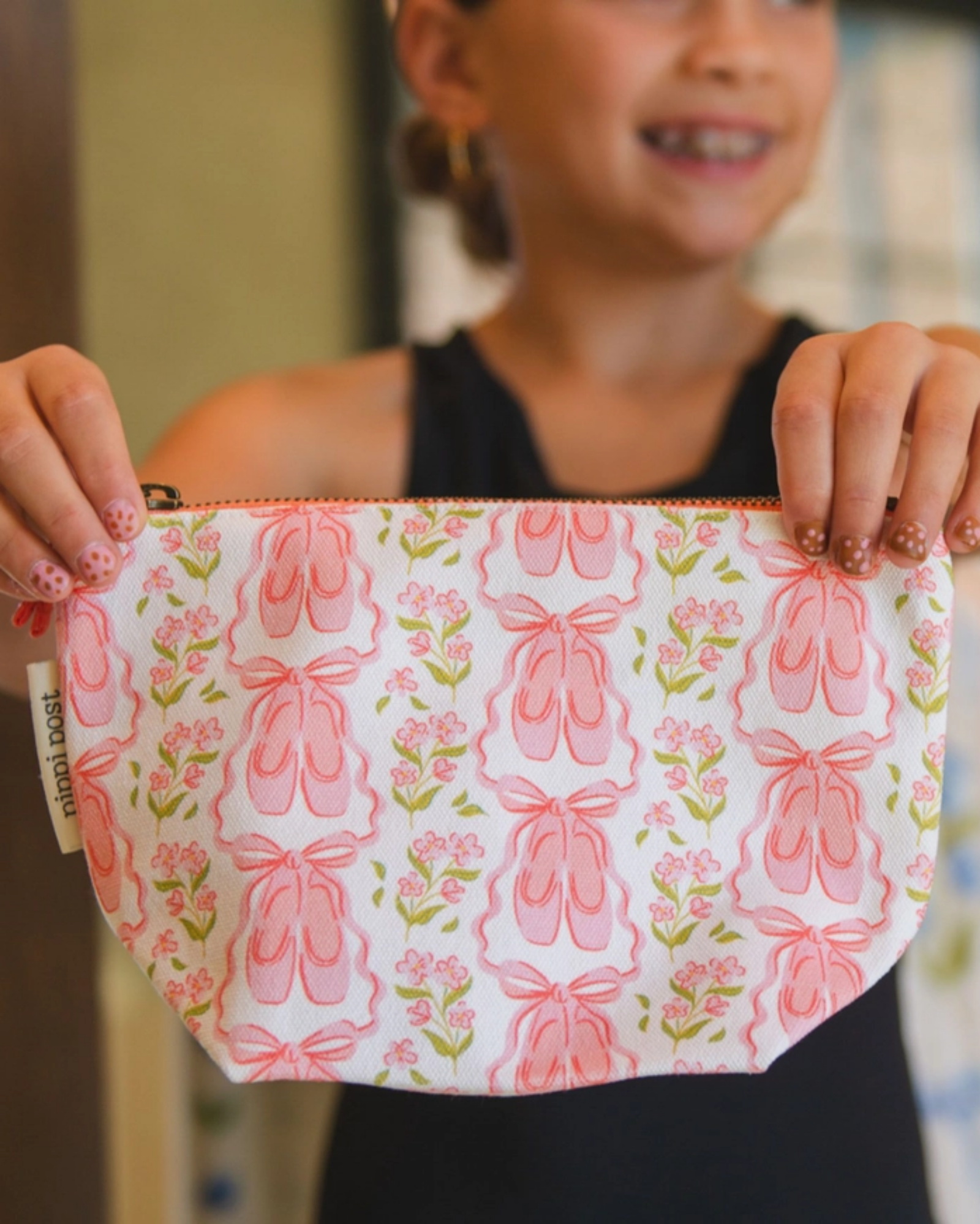 Person holding a pink pouch with ballet slipper design