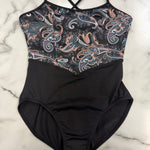 A leotard with a solid black lower body and a black, blue, and peach paisley patterned upper chest, laid flat on a white marble surface.
