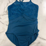 A blue leotard with a textured, tonal zebra pattern on the upper bodice and solid blue straps, laid flat on a white and gray marble surface.